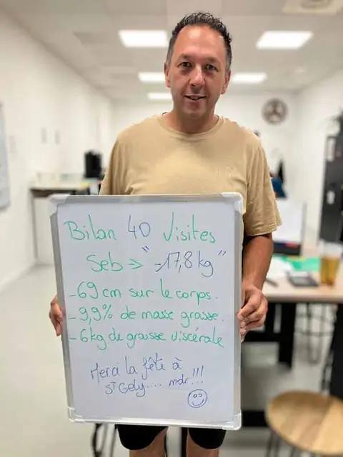 Au club, un membre souriant montre le bilan écrit sur son ardoise