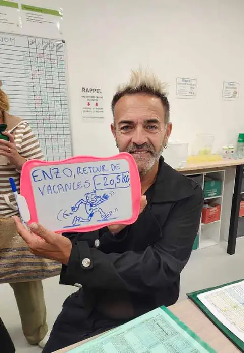 Au club, un membre souriant montre le bilan écrit sur son ardoise