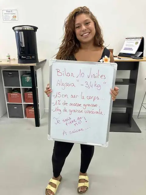 Au club, une membre souriante montre le bilan écrit sur son ardoise